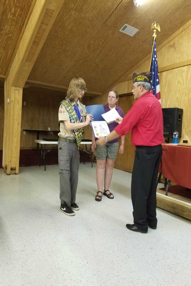 Evan Nettles receives his certificate and check for K. Hammond. Gina Rhoden looks on.